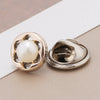 A pair of gold-toned pearl and rhinestone no-sew brooch buttons resting on a white card.