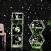 A set of clear glass hourglass timers filled with green liquid and featuring panda and mushroom designs on a dark surface.