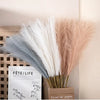 A close-up of pink and white artificial pampas grass stems displayed in various arrangements.
