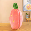 A pink plush strawberry shaped pillow with yellow dots, resting on a wooden table.