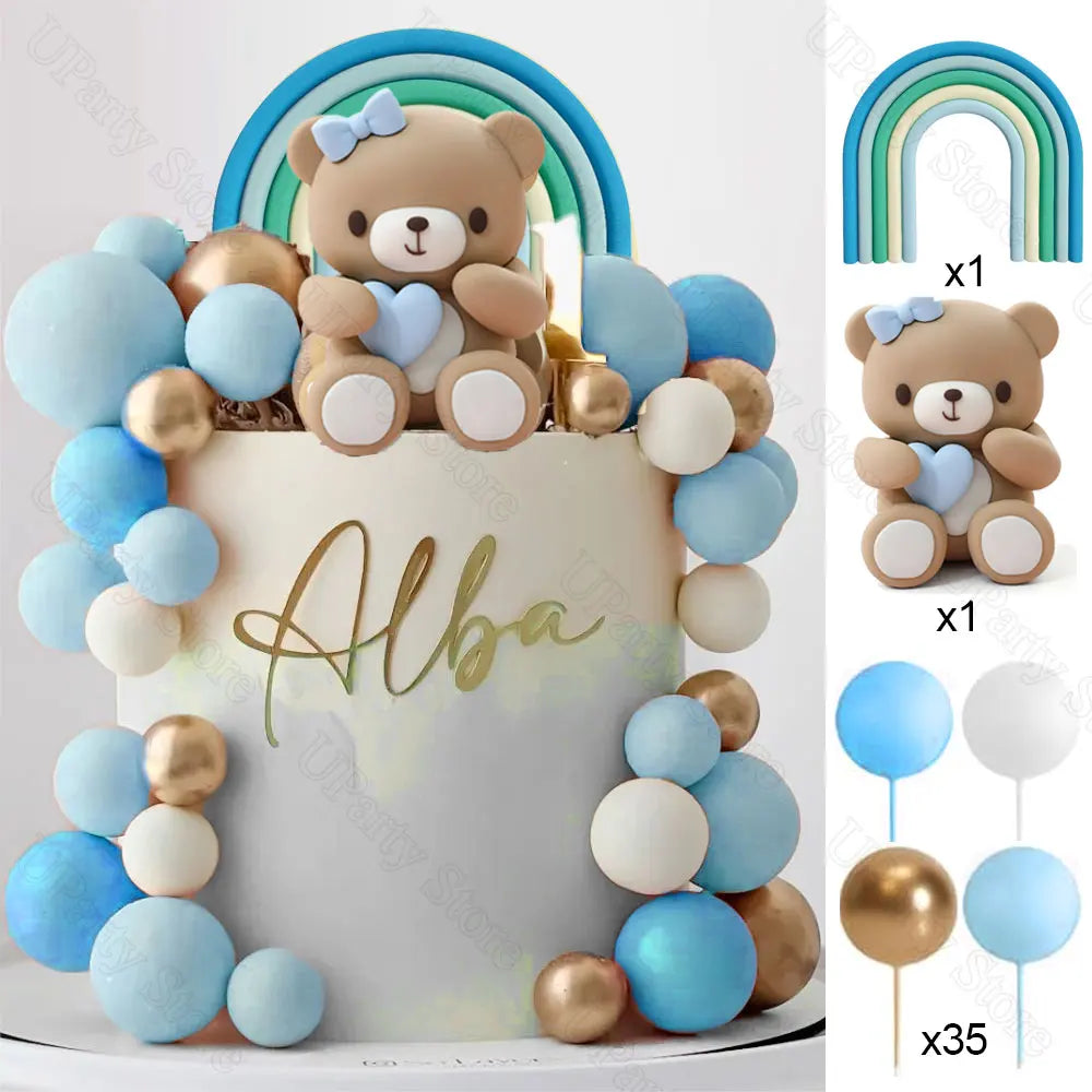 A white cake decorated with blue and gold ball decorations and a rainbow arch topper.