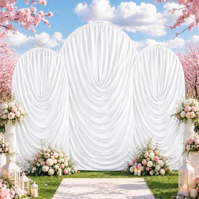 A white draped arch cover decorated with pink blossoms and floral arrangements for a wedding or event backdrop.