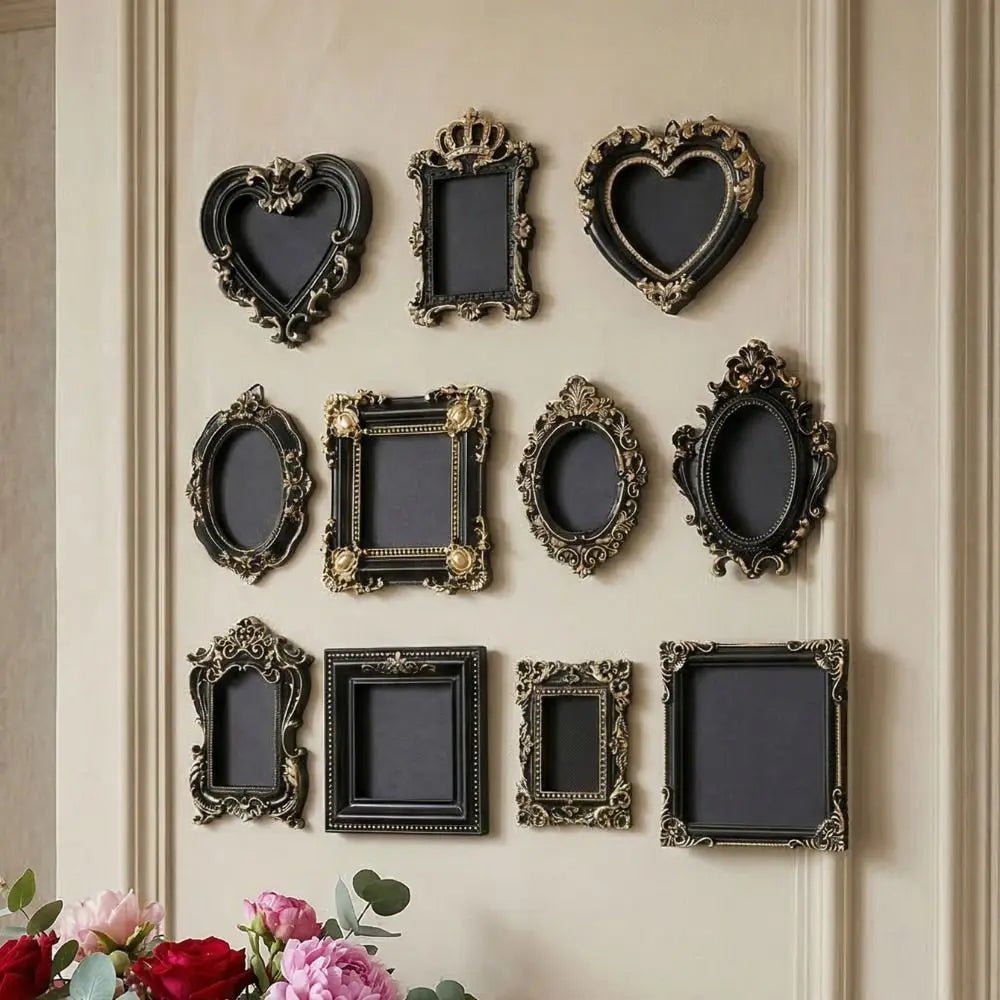 A collection of vintage baroque resin hanging photo frames in black and gold on a cream-colored wall.