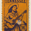Vintage Tennessee postage stamp featuring a woman playing a guitar.