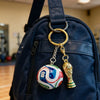 A gold-colored FIFA trophy keychain hangs from a dark blue backpack zipper.