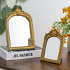 A vintage gold-framed arched vanity mirror resting on a white box with the name Jil Sander.