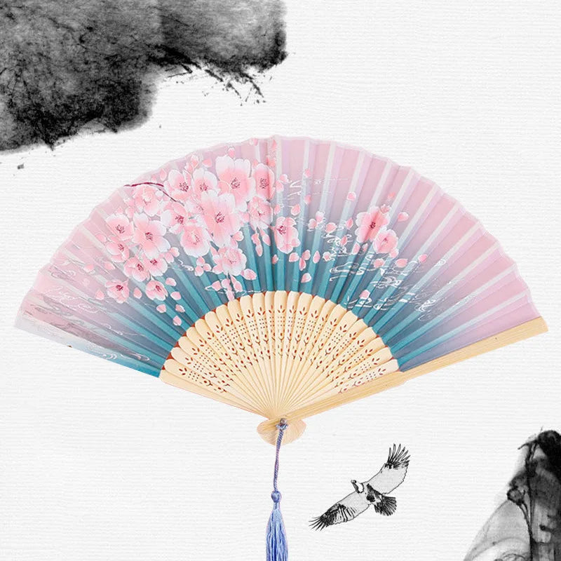 A vintage bamboo folding hand fan with pink and blue floral accents is shown against a white background.