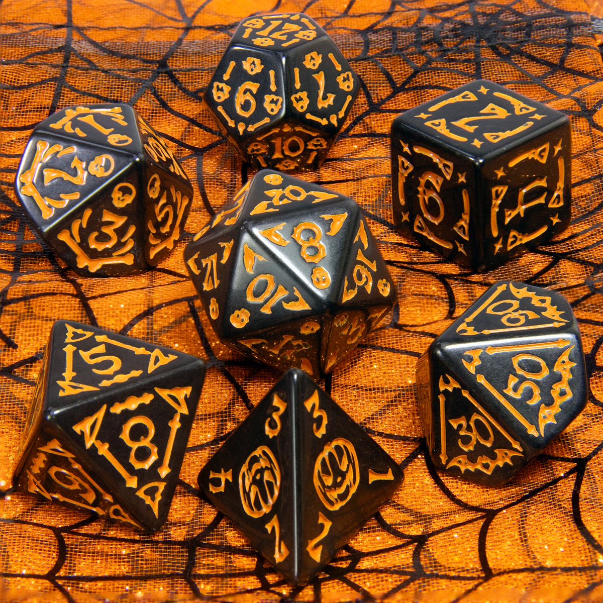 A collection of nine black polyhedral dice scattered on an orange mesh surface.