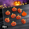 A variety pack of 50 orange Halloween pumpkin resin nail charms displayed on a dark gray surface.