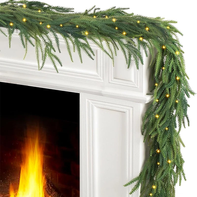 Green Norfolk pine Christmas garland with warm lights draped over a white fireplace mantel