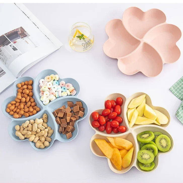 A heart-shaped four-compartment snack tray filled with various nuts, candies, and dried fruits.