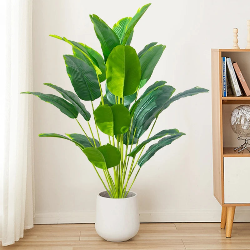 Artificial tropical palm tree with large green monstera leaves in a white pot
