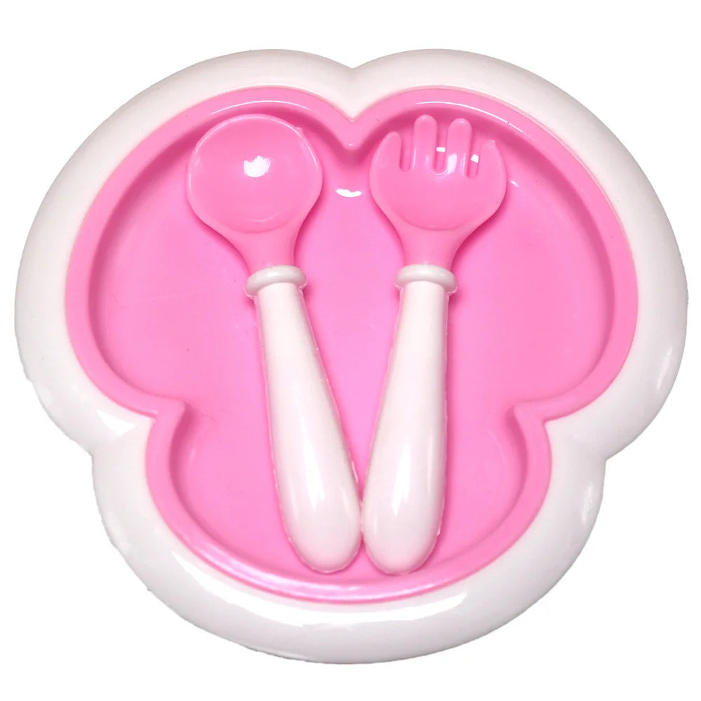 A pink silicone mold shaped like a heart containing a plastic spoon and fork.