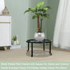 A decorative metal plant stand with a saucer holding a large green plant in a silver pot on a wooden surface.