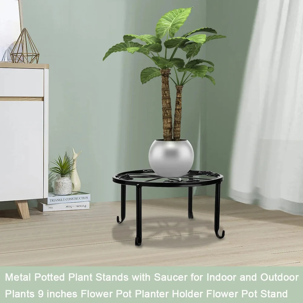 A decorative metal plant stand with a saucer holding a large green plant in a silver pot on a wooden surface.