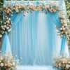 A light blue tulle backdrop decorated with floral garlands and draped fabric for an elegant event.