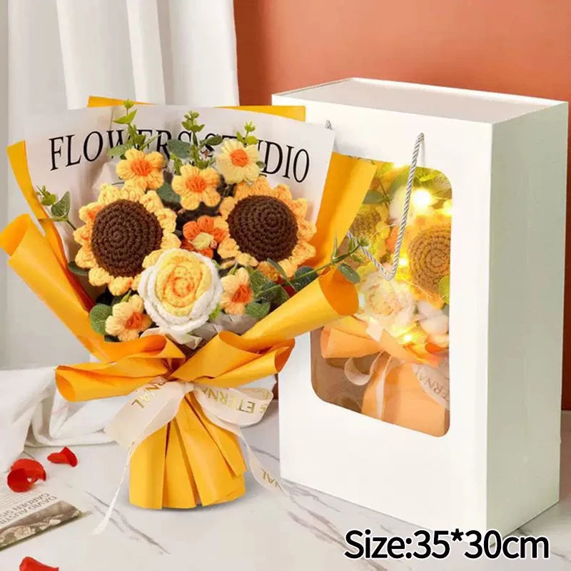 A handmade crochet flower bouquet in yellow and orange is displayed inside a white box.