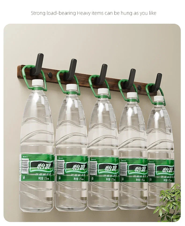 Eight hooks on a wooden coat rack displaying five glass bottles of water.