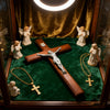 Hand-carved wooden cross wall decor displayed in a glass box with angels and green velvet fabric