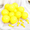 A collection of bright yellow latex balloons scattered on white sheer fabric.