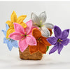A hand-crocheted bouquet of colorful artificial lily flowers in shades of yellow, pink, purple, and white, displayed in a wov