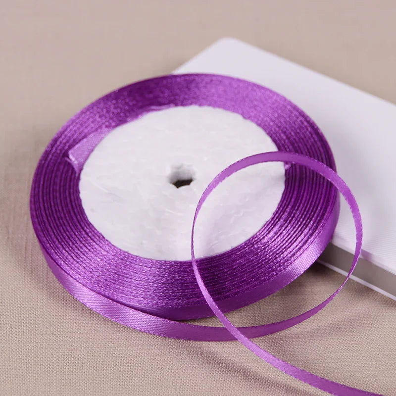 Purple satin ribbon spool with a white center, used for gift wrapping and crafts.