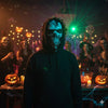 A person wearing a dark hoodie with a realistic skull mask in a dimly lit party setting.