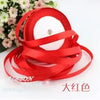 Red silk satin ribbon rolled into a coil on a white background.