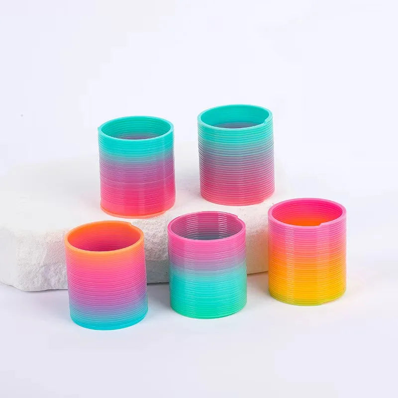 A set of six colorful, striped silicone cups in rainbow colors arranged on a white surface.