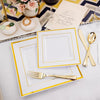 A set of gold plastic dinnerware plates and cutlery is displayed on a white tablecloth with floral accents.