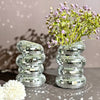 A clear mirror tile disco ball vase filled with purple flowers, set against a gray background.