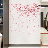 Wall decal featuring pink peach blossom branches and falling petals on a white background