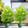 A set of two realistic artificial floor plants with large green leaves displayed on a white surface.