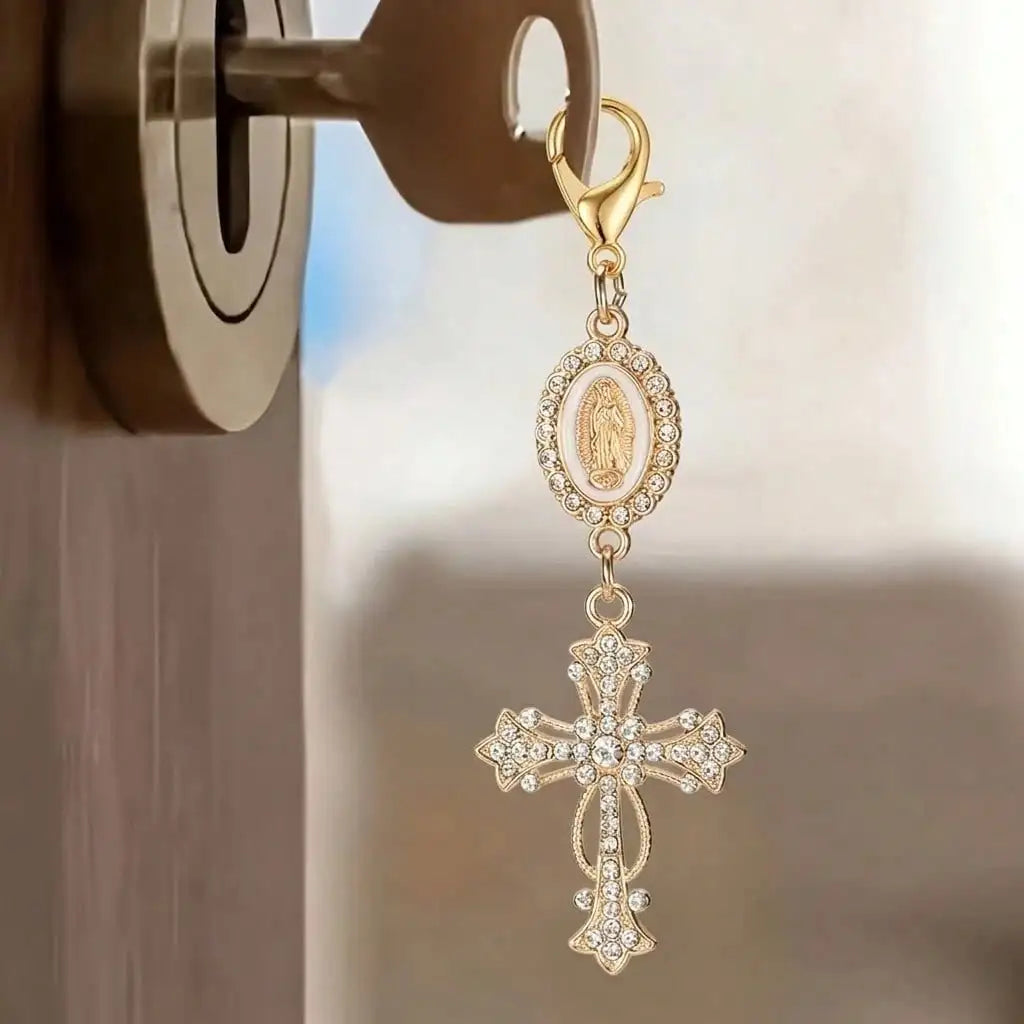 Gold pearl rhinestone cross keychain charm hanging from a door hook.