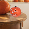 An orange carved pumpkin decoration with a smiling face and three white triangles on its front