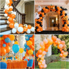 A close-up of an orange balloon arch decorated with black and white balloons for a party.
