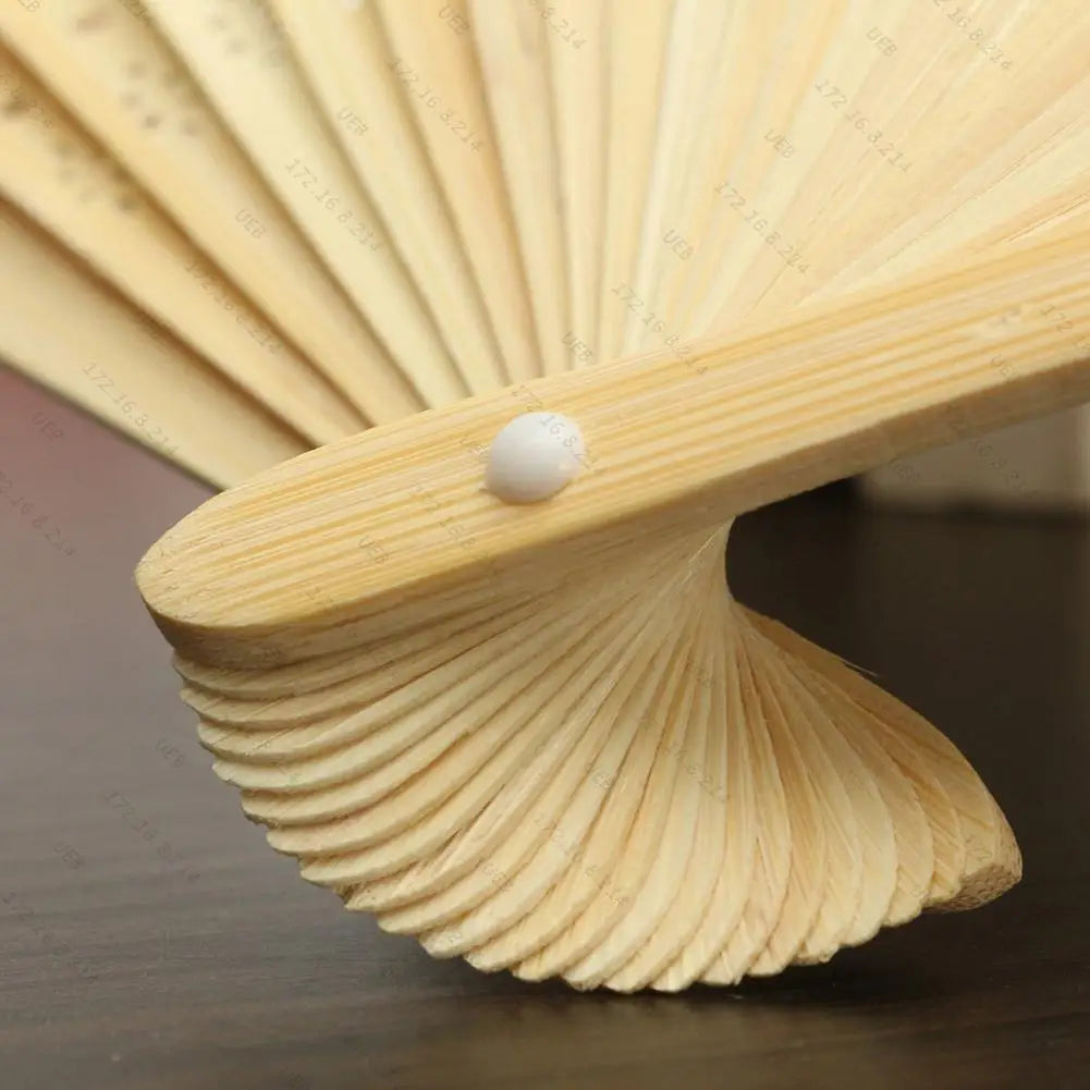 A close-up of a light yellow bamboo folding fan with white accents, showing the layered fan blades.