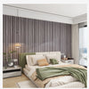 A bedroom featuring a bed with light green bedding and wood grain wallpaper accent wall.