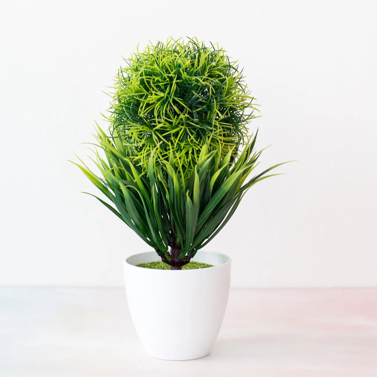 Un vibrant arbre bonsai vert artificiel avec un feuillage dense, en pot en céramique blanche.