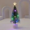 Ein kleiner, dekorierter Weihnachtsbaum mit grünen Lichtern und Sternspitze auf weißem Sockel.
