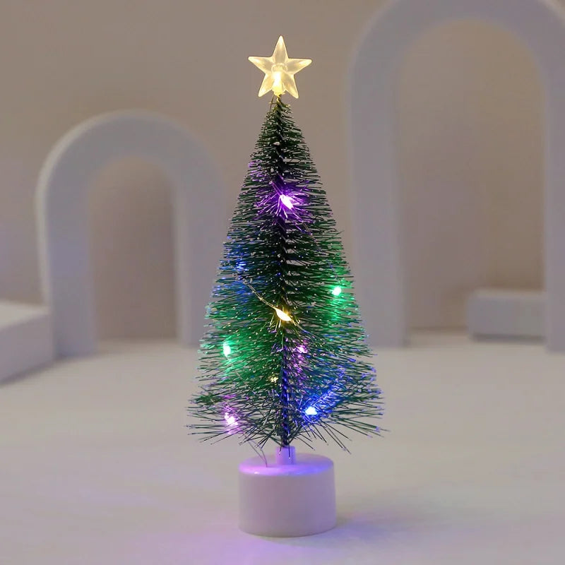 Ein kleiner, dekorierter Weihnachtsbaum mit grünen Lichtern und Sternspitze auf weißem Sockel.