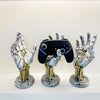 A display of three hand-shaped metal organizers designed to hold a 3D gamepad or controller.