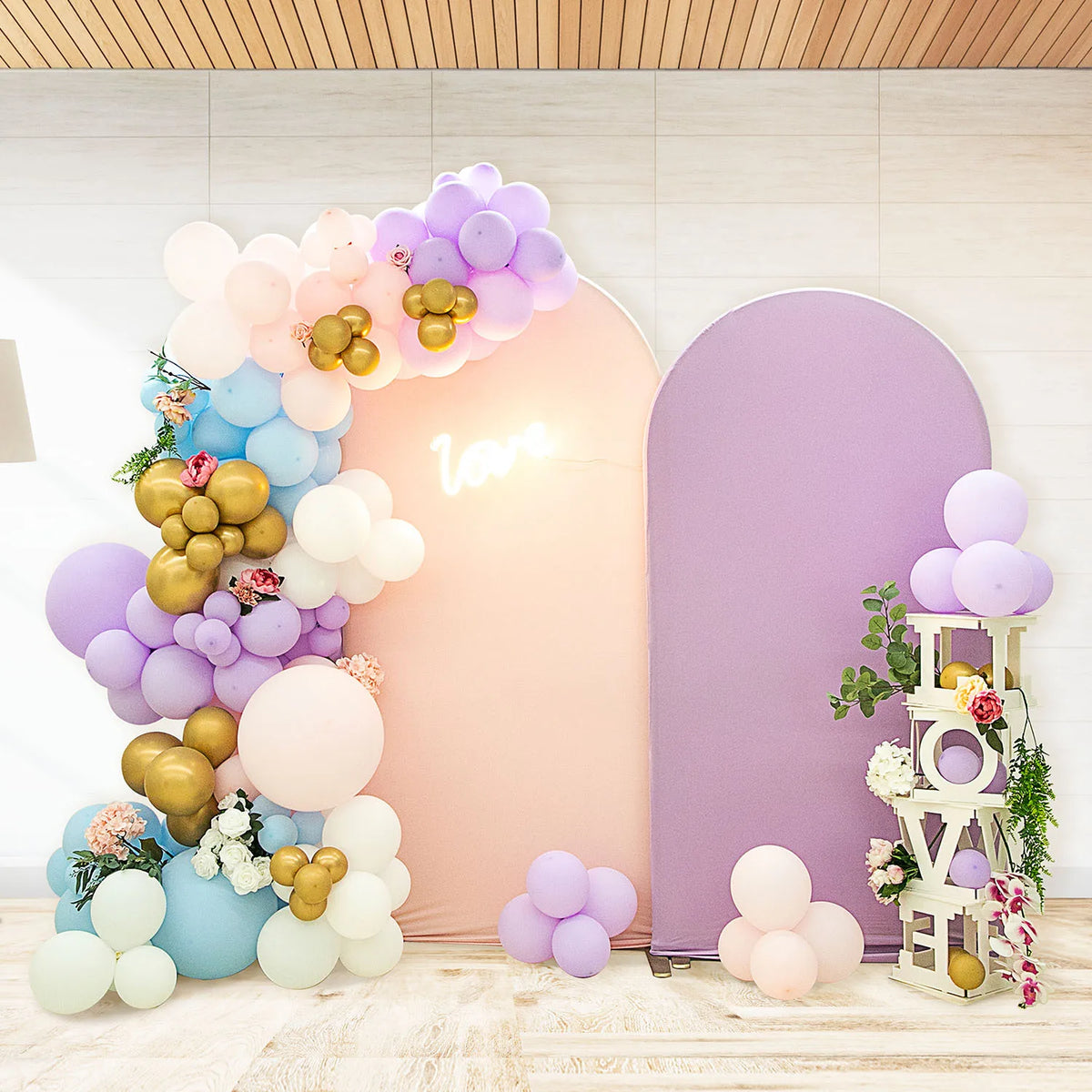 A floral balloon arch backdrop featuring pink and purple balloons against a light wall.