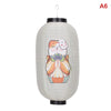 A white paper hanging lantern with a smiling face design, suspended by a black hook.