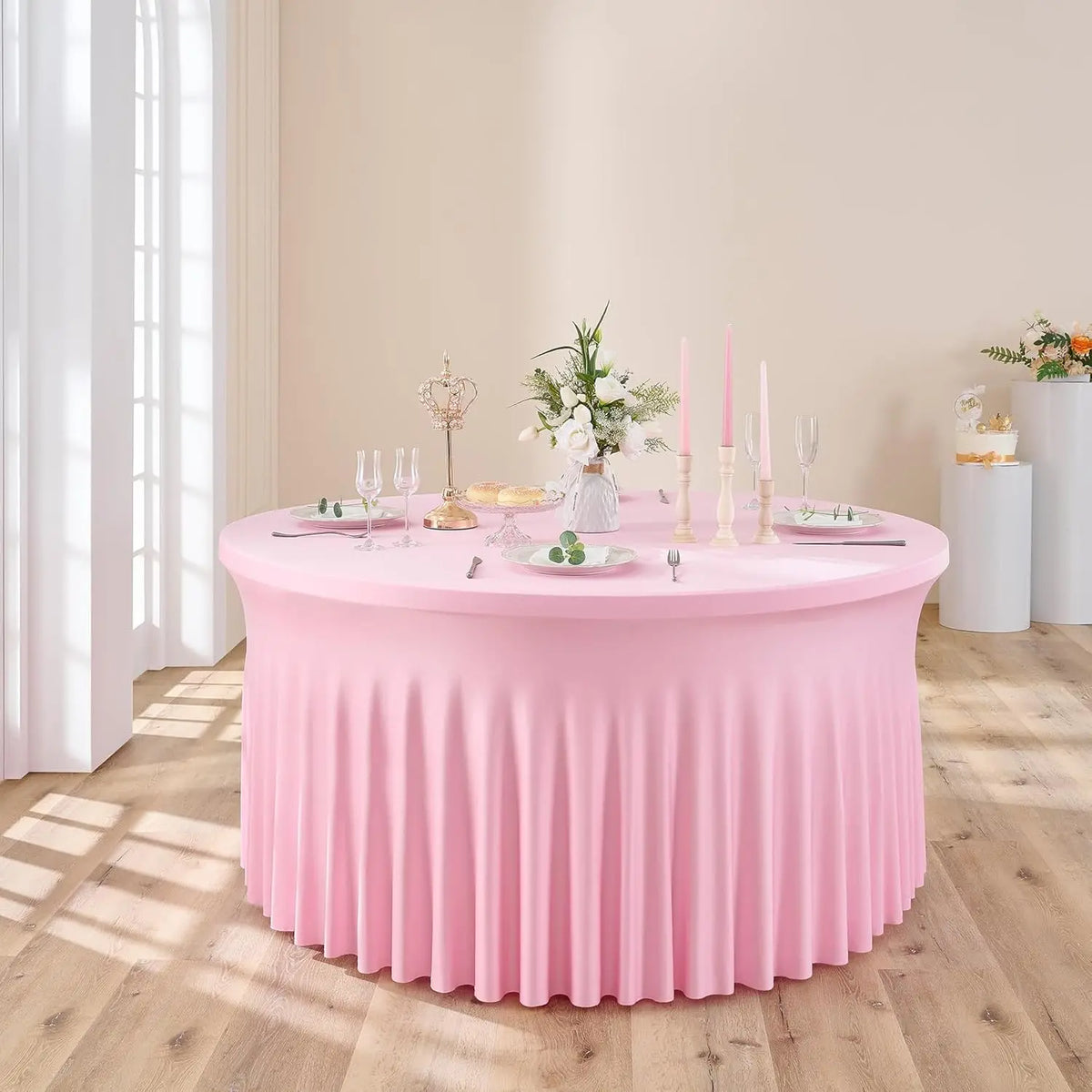 A pink stretch spandex round tablecloth with a pleated skirt set for an elegant table setting.