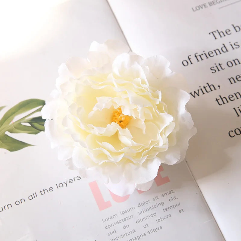 A white peony flower decoration placed on a page with text and a green palm leaf.