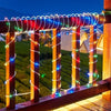 A wooden railing decorated with colorful LED rope lights illuminating a scenic outdoor view at night.