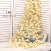 A long garland of artificial pale yellow sakura flowers draped against a white wooden background.
