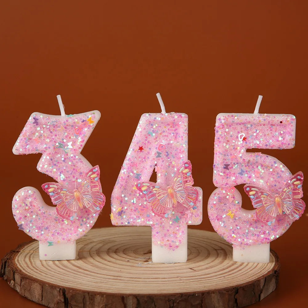 Pink butterfly number birthday candles displaying the numbers 3, 4, and 5 on a wooden surface.