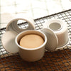 A set of five light beige non-stick round cake molds with removable bases resting on a wire rack.